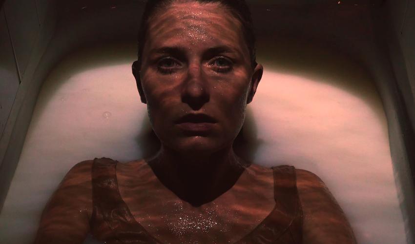 Bild på skådespelaren Ylva Olaison i ett badkar. Hon tittar in i kameran. 